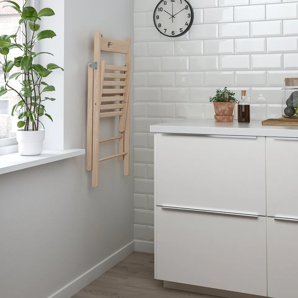 Kitchen with chair, cabinets, plant, clock, counter items.