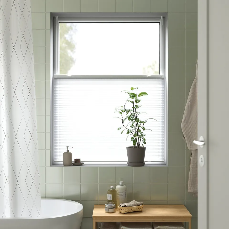 Modern bathroom window with HORNVALLMO blinds, green tiles, plant, and towel.