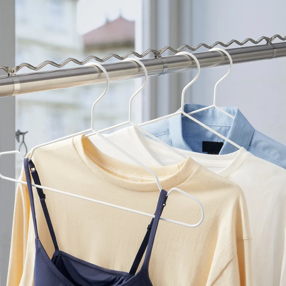 Clothes rod with pleated, adjustable design, holding white sweater and blue garment, suitable for balcony drying or airing.
