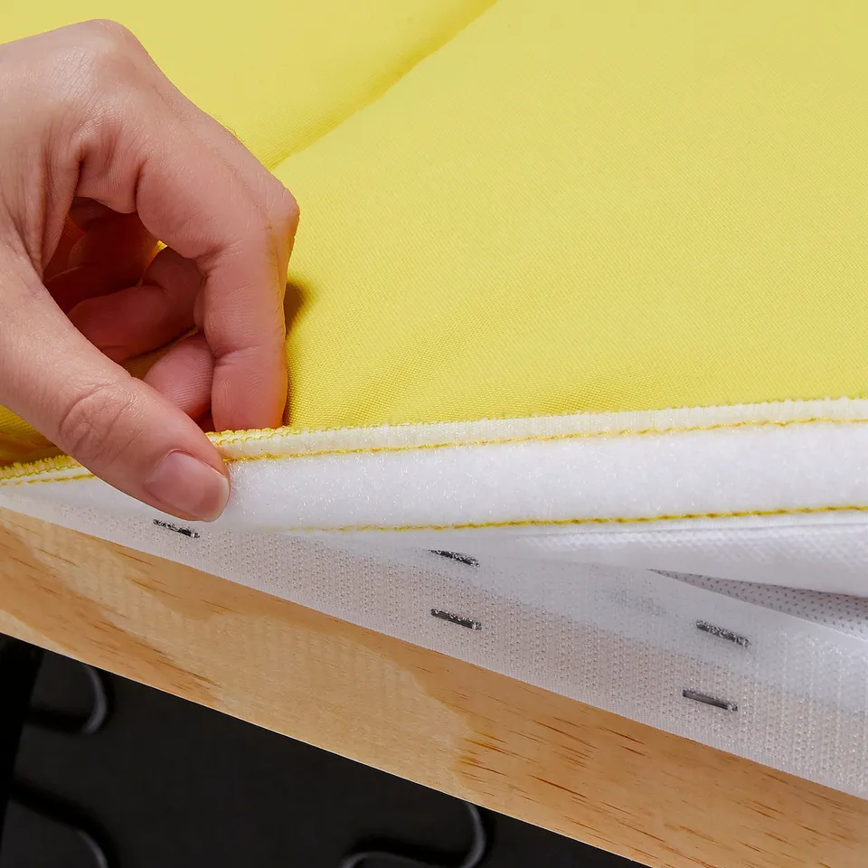 Hand holding yellow fabric with white stripe and clips.