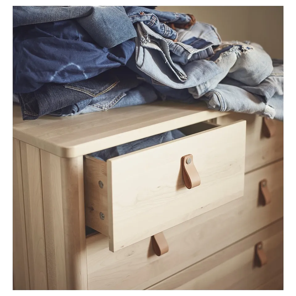 Light wood dresser with open drawer and folded jeans.