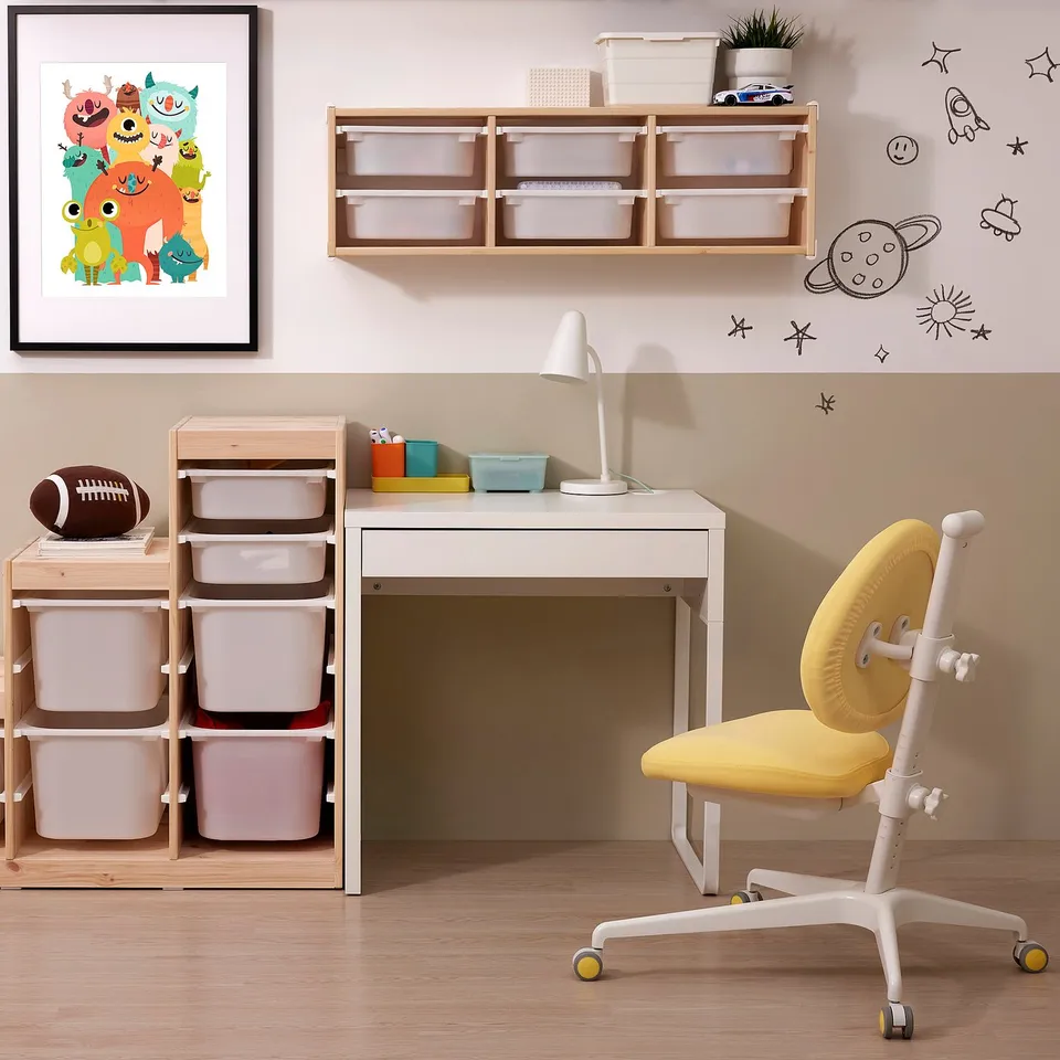 A kids study area with a small white desk, yellow chair, and storage.