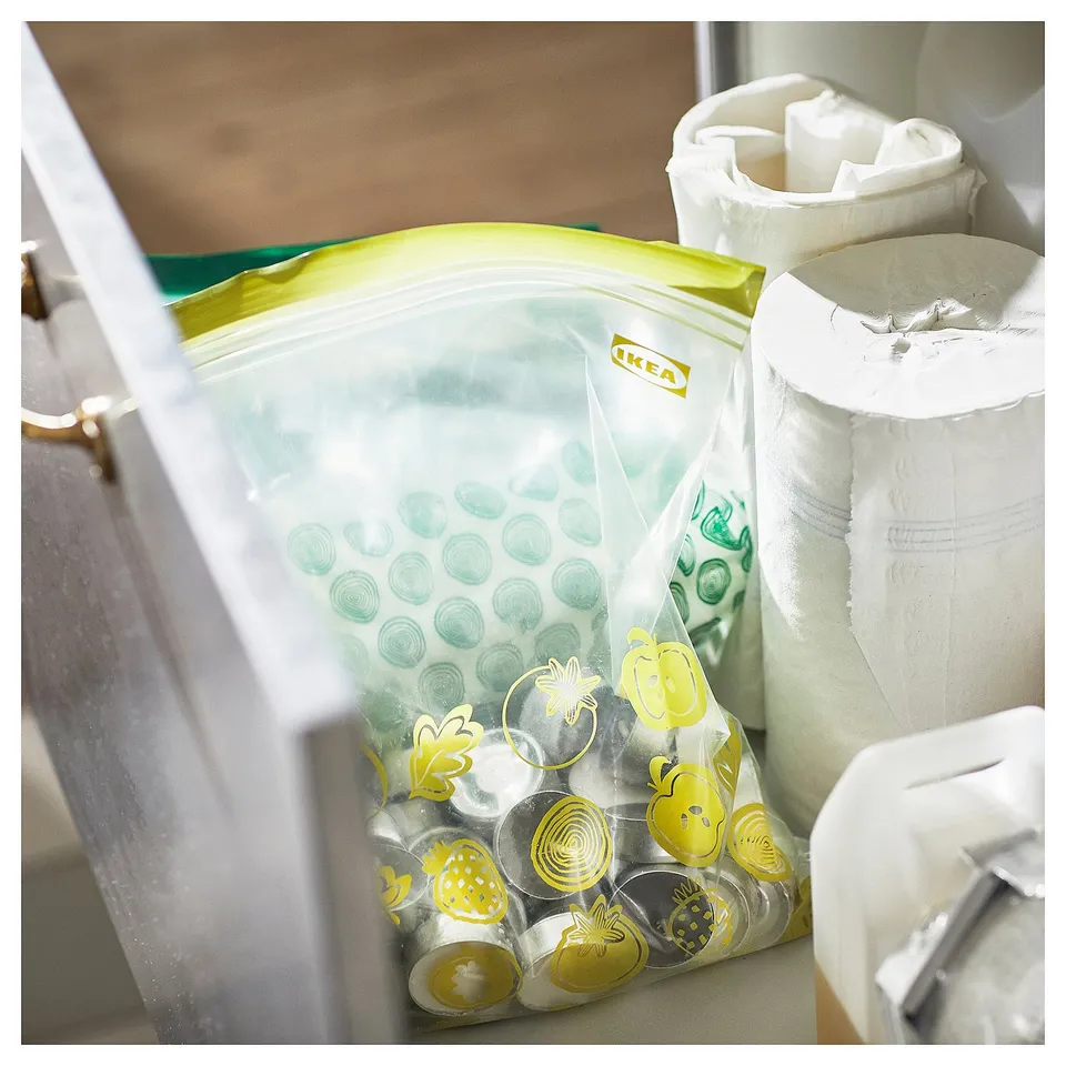 IKEAs green and yellow reusable storage bag with various designs, placed inside a drawer.
