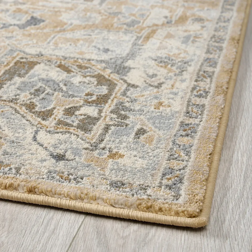 Nicely textured, pastel area rug with intricate patterns, laid on wooden floor.