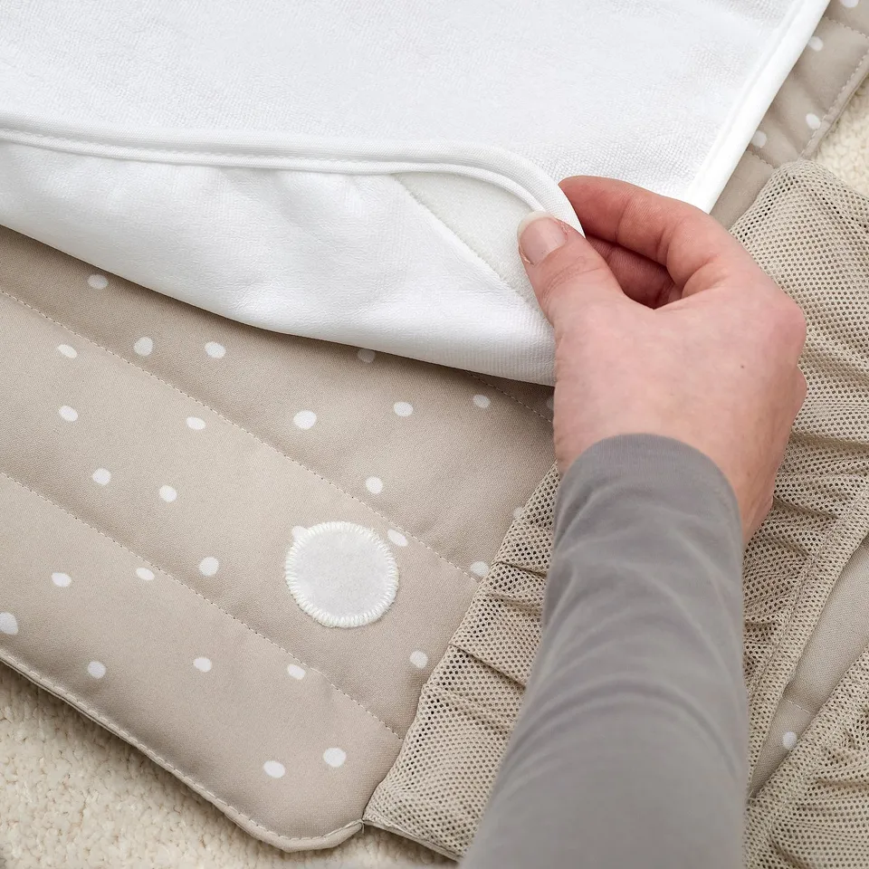 A hand folding a changing pad with polka dot fabric.
