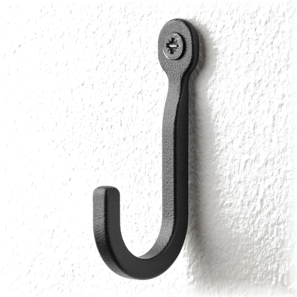 Black wall hook, curved, securely fastened. Black hook on wall, curved, secure.