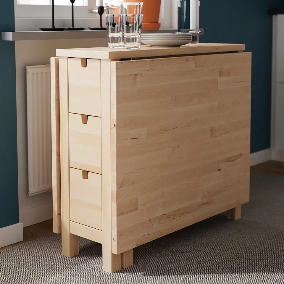Wooden drop-leaf table with drawers and glasses on top.
