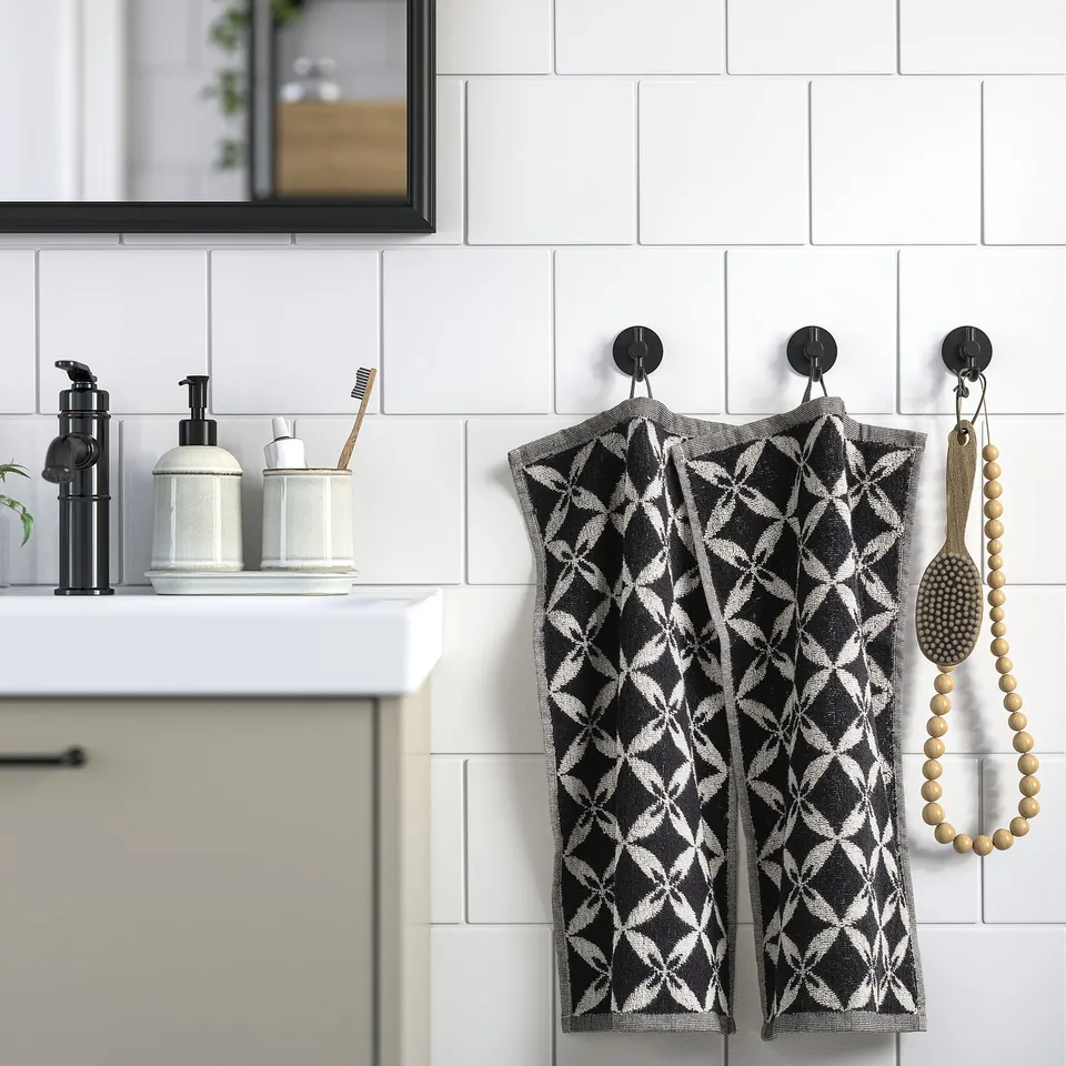 Black & white towels hang by sink. Diamond-patterned, thin, with hooks.