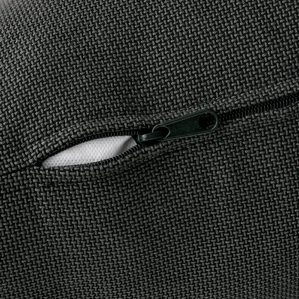 Close-up of a zip on a textured black sofa, showcasing quality fabric.