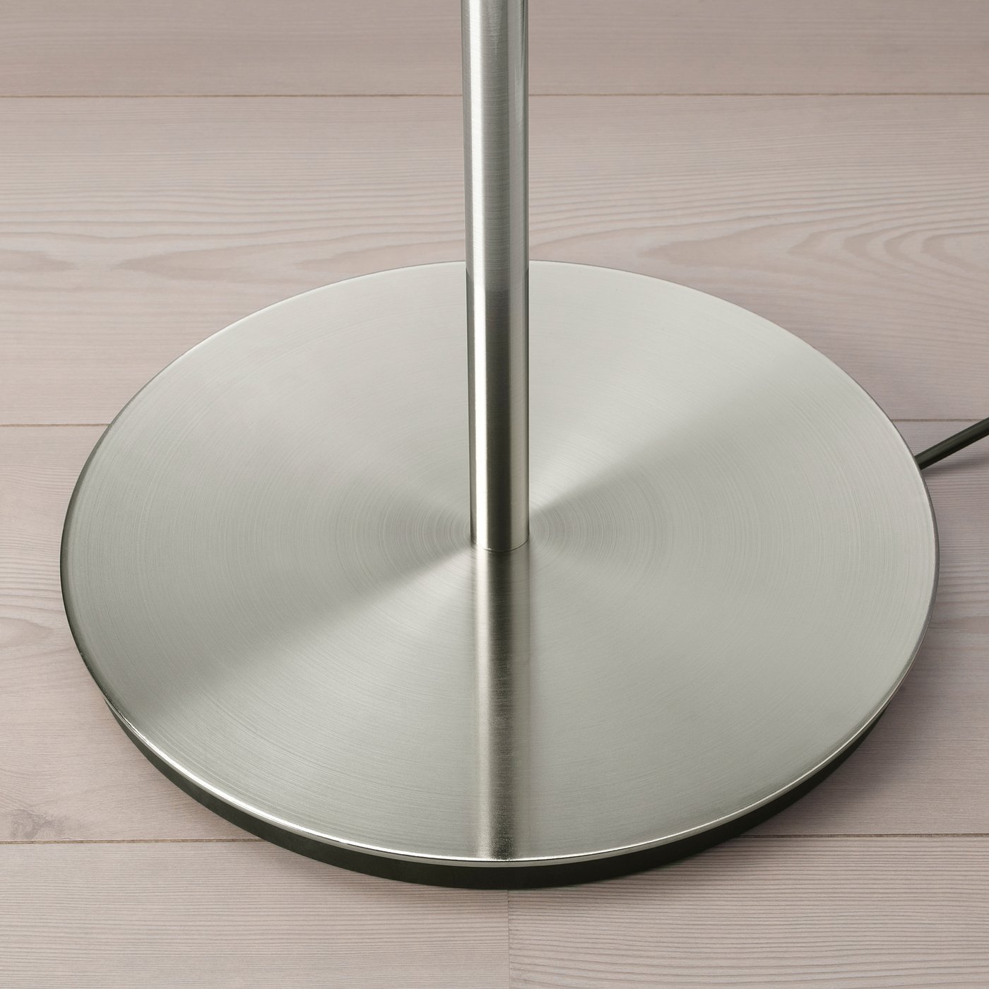 Silver metal base, part of stylish lamp series, sits on wooden floor. Modern design, quality finish.