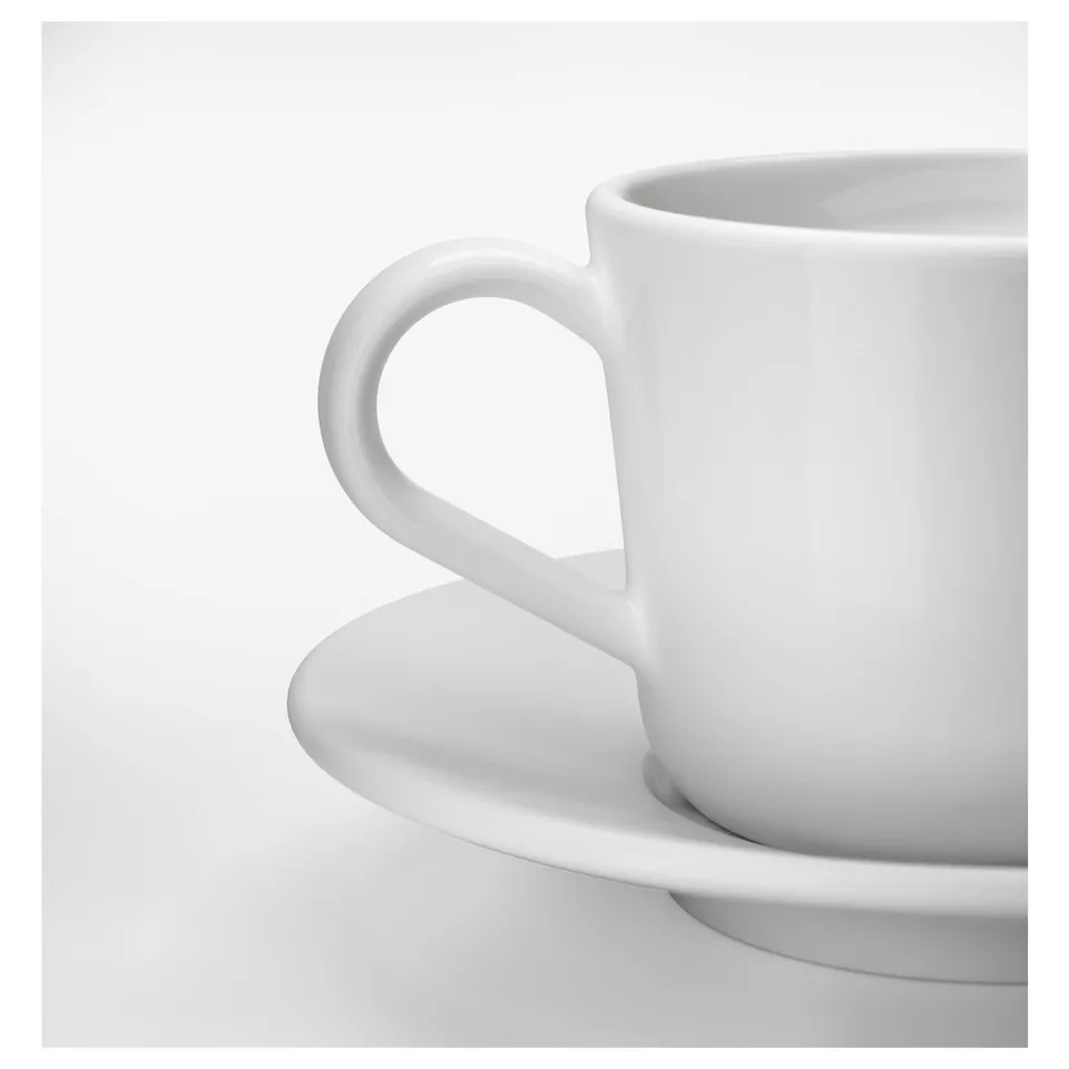 A pristine white mug with a smooth handle sits elegantly on a matching saucer, showcasing its sleek design and high-quality porcelain finish.