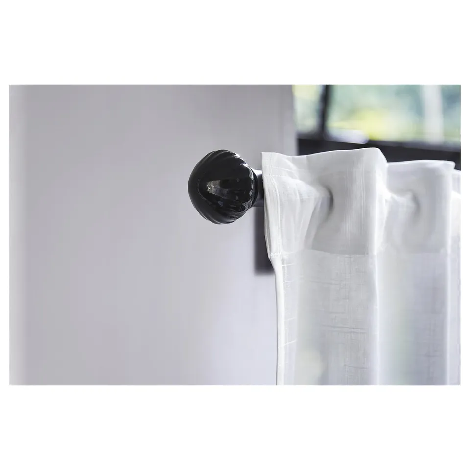 Black ceramic sphere finial on white curtains.