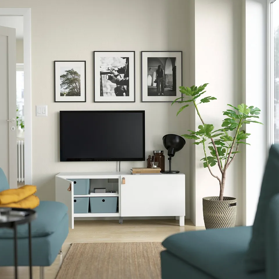 Modern living room with BESTÅ tv stand, adjustable shelves, flat-screen tv, photos, lamp, plant.