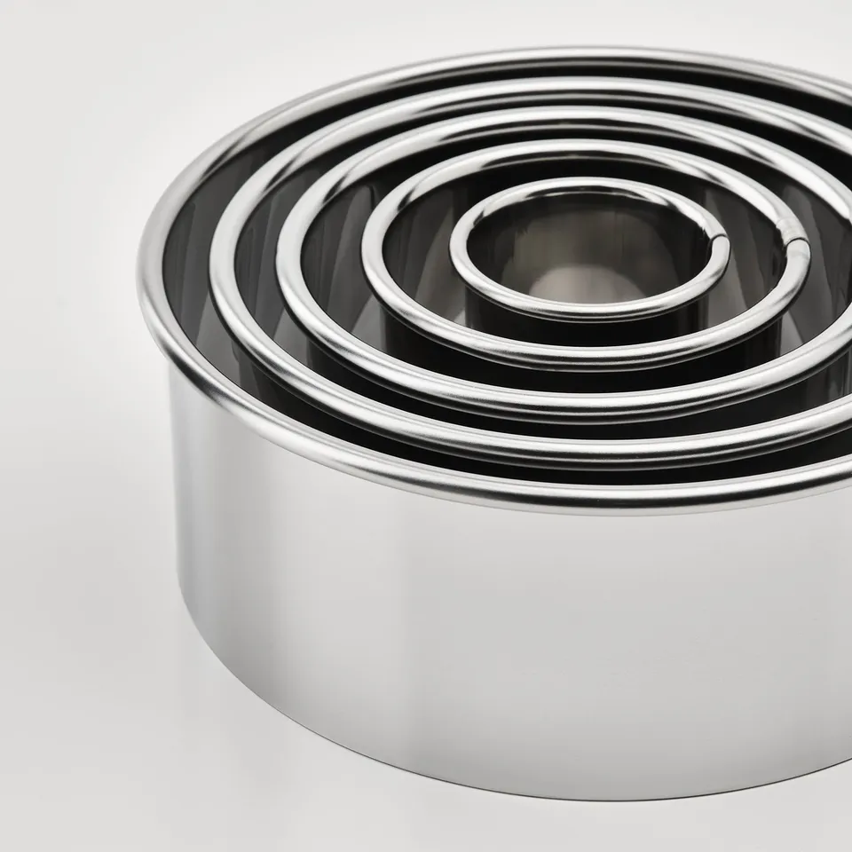 Stack of stainless steel cookie cutters, various sizes. Shiny, metallic finish.