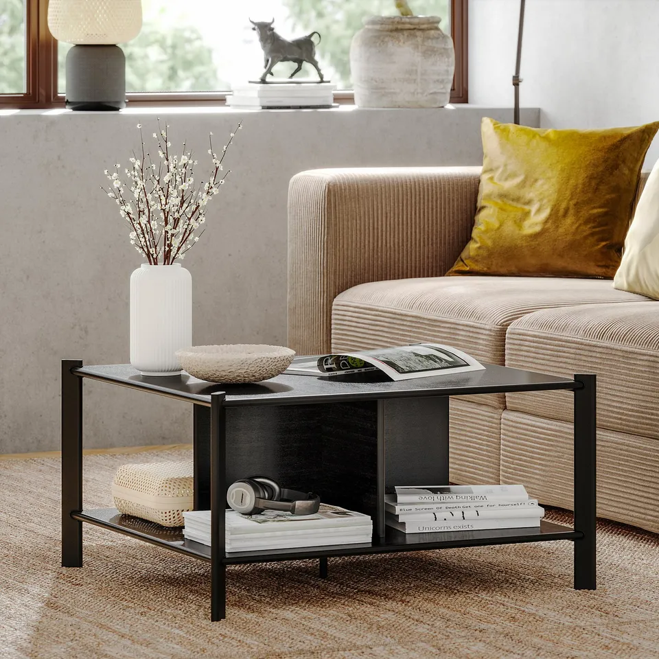 Modern living room with JÄTTESTA black metal coffee table, yellow pillows, white vase with flowers, books, and bull statue on window ledge.