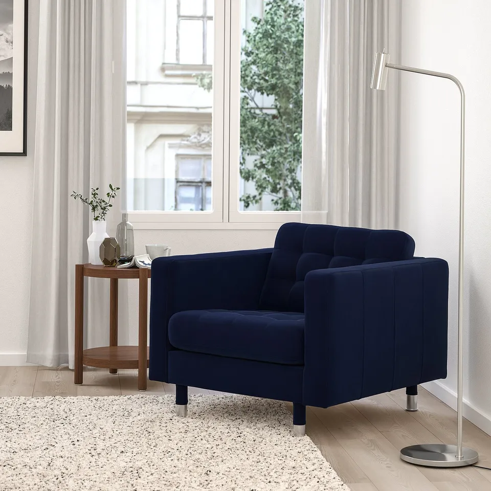 Blue velvet LANDSKRONA armchair by window, table & lamp.