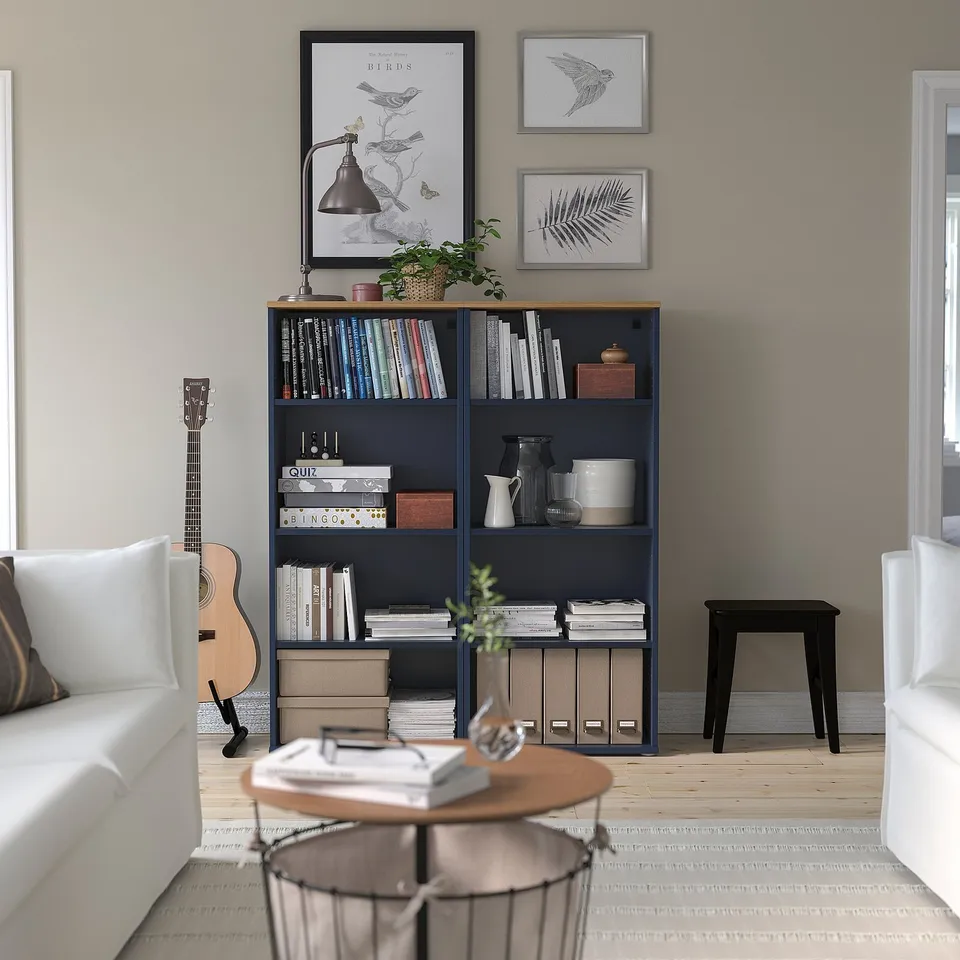 Cosy living room with SKRUVBY bookcase, art, couch, coffee table, armchair, and guitar.