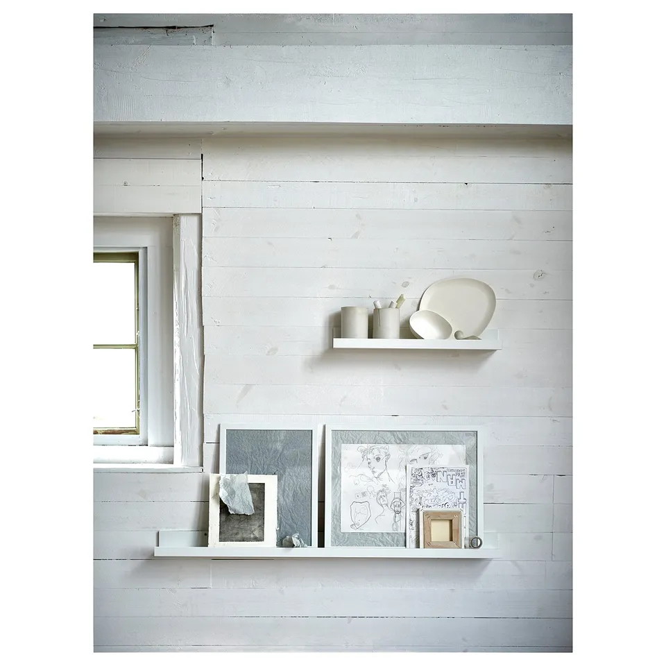 Minimalist wall decorated with MOSSLANDA white picture ledges displaying art prints and ceramic decorations.