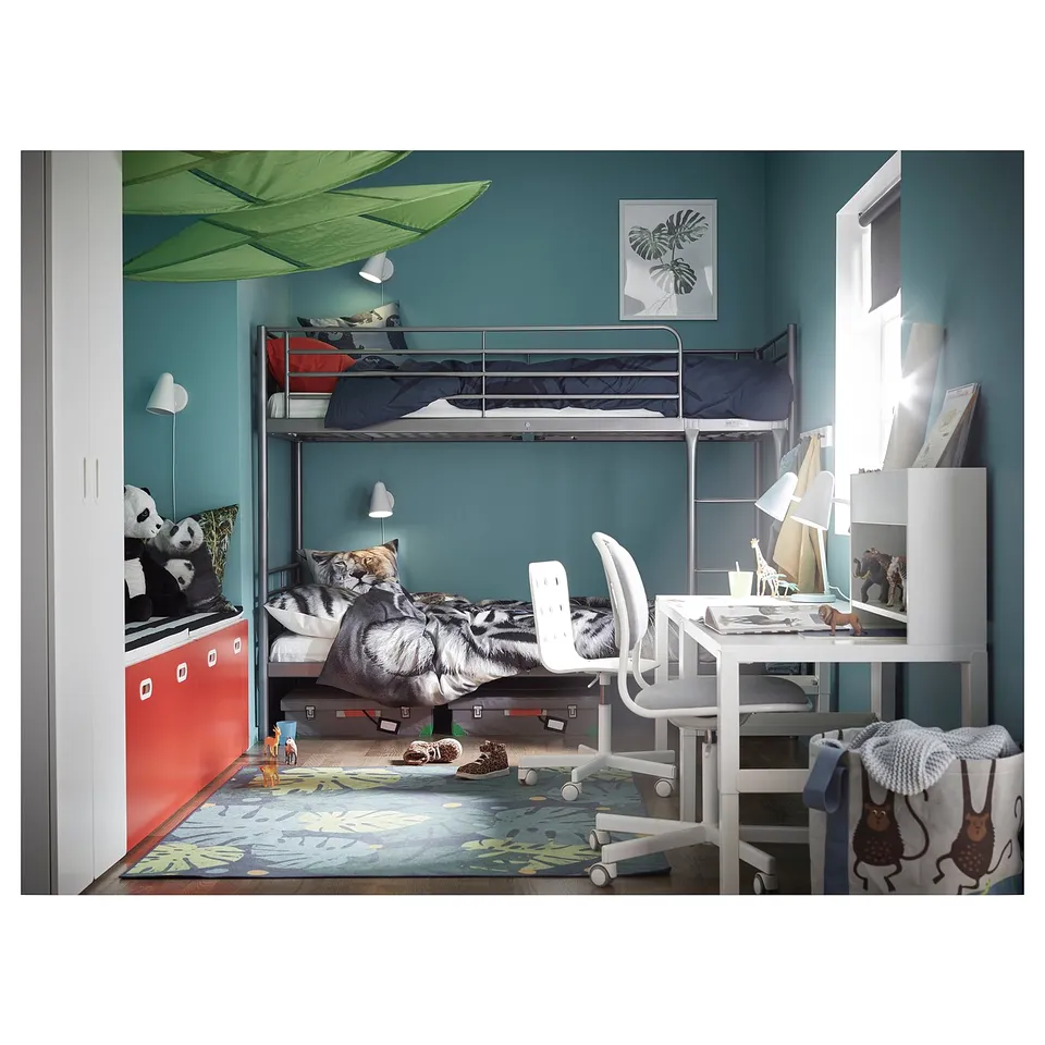 Kids bedroom with blue-green walls, SVÄRTA metal bunk beds, colourful pillows, a white desk with chair, and a green rug.