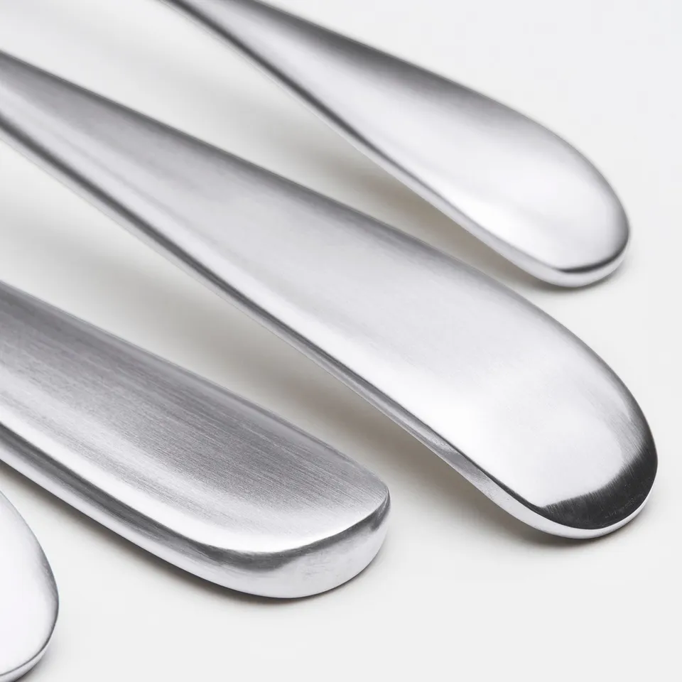 A set of polished stainless steel knives displayed neatly on a white surface. Blades are smooth and reflective.