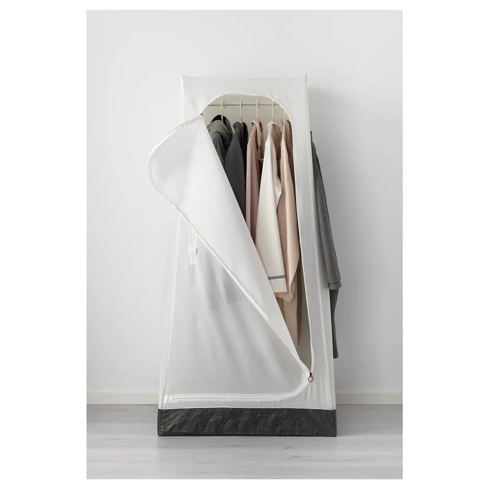 A freestanding wardrobe with a white cover, holding several hanging garments, secured to the wall, and featuring hooks on the sides.