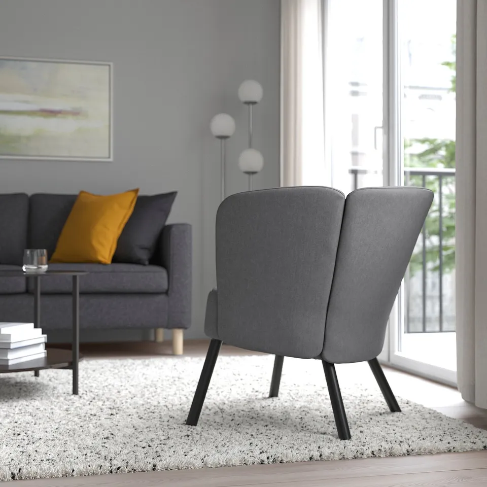 Modern living room: grey upholstered armchair, couch, coffee table, and large window.