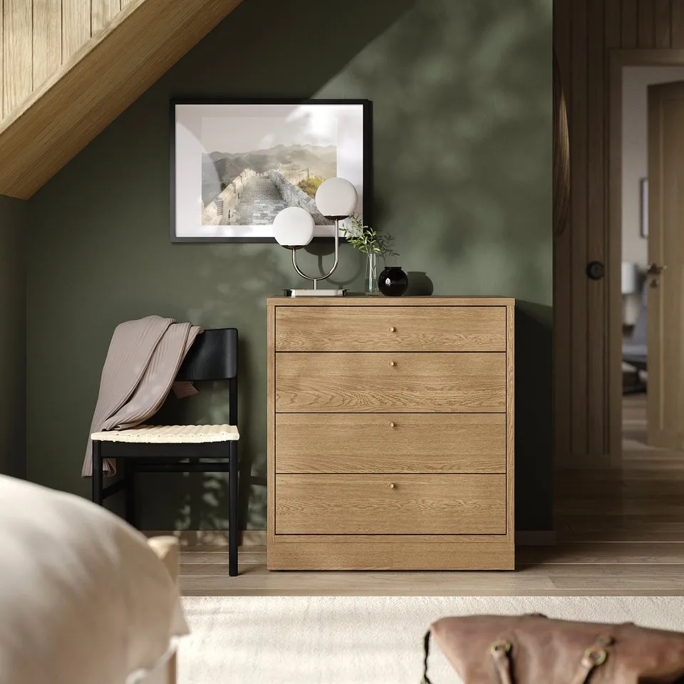 TONSTAD light wood chest with gold knobs beside black chair.