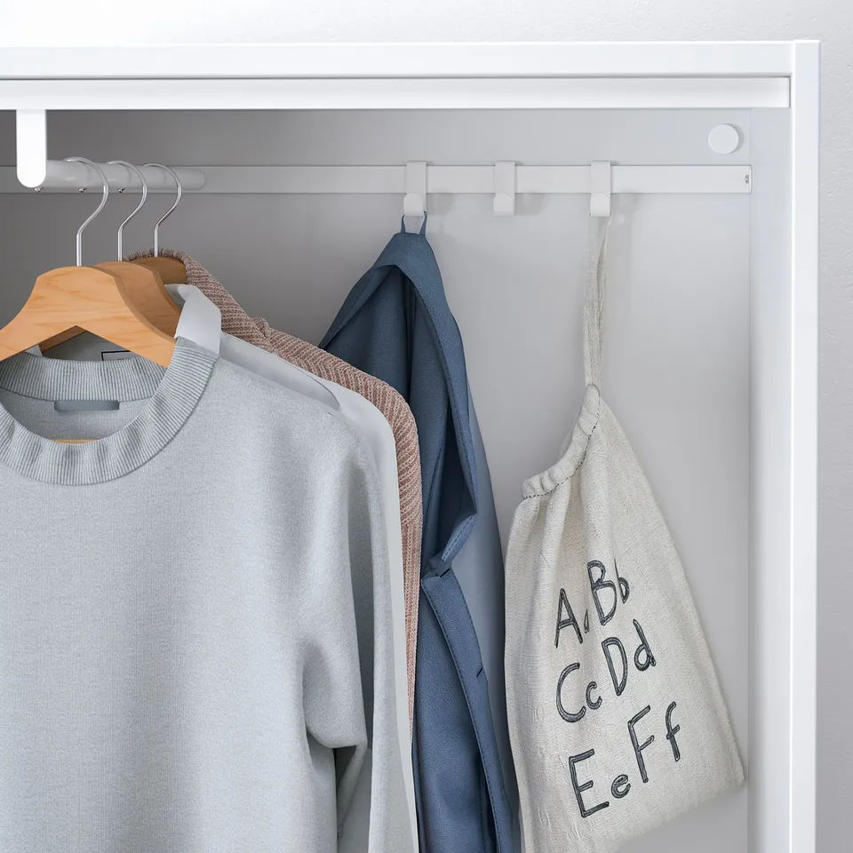 White clothes rail in shallow closet; holds several hanging garments, including a grey sweater and blue jacket.