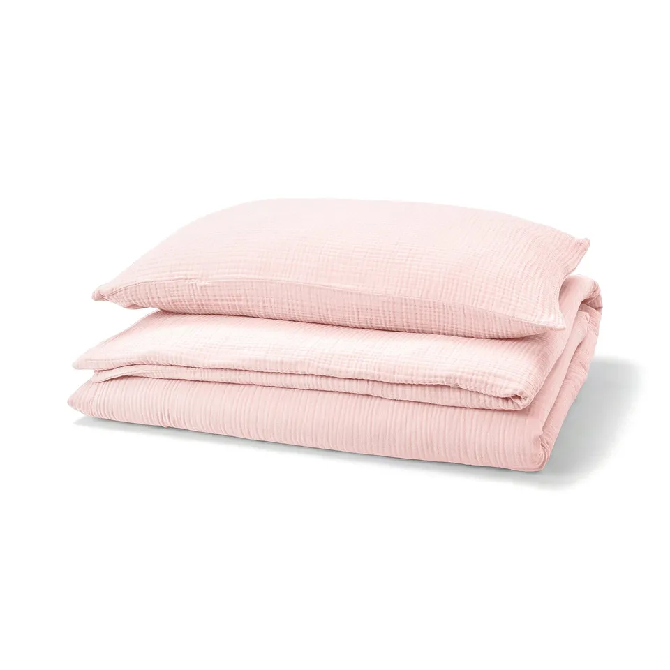 Stacked light pink SCHERSMIN cotton bedding set with textured design.
