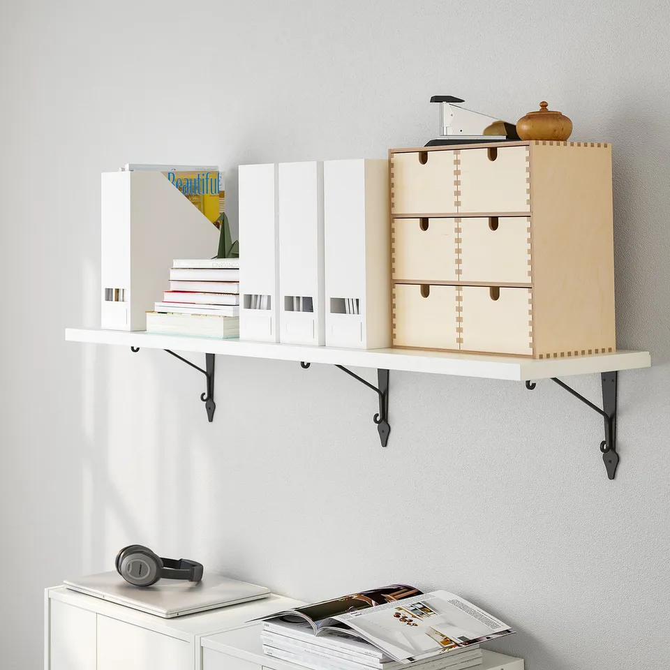 Wall-mounted shelf with books, organisers, and a cabinet with headset and magazines.