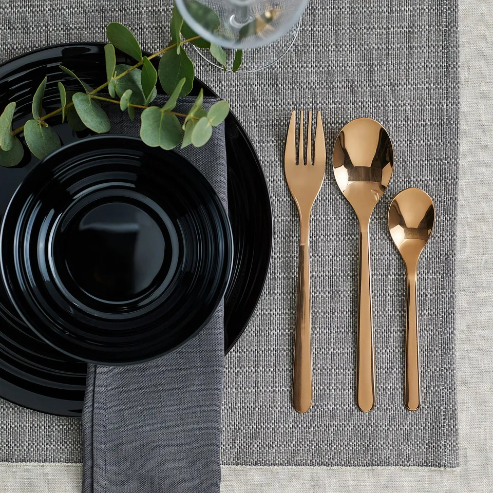Gold cutlery set on black plate. Elegant & durable for special or daily use.