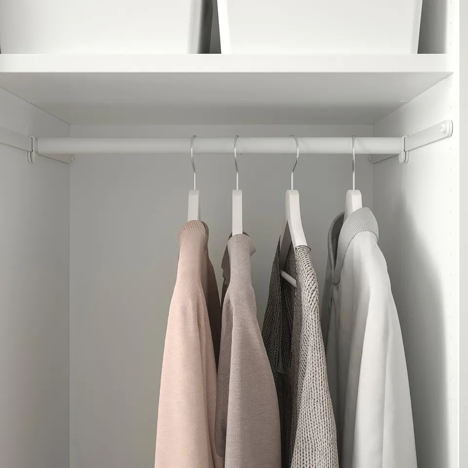 Closet with adjustable rail, featuring four hangers holding clothes, part of the IKEA HJÄLPA organisational system.