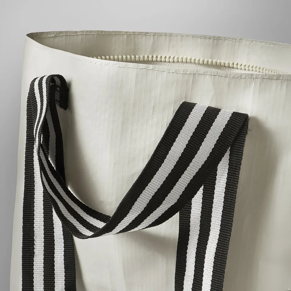 Close-up of sturdy, black and white striped handle on durable white bag.