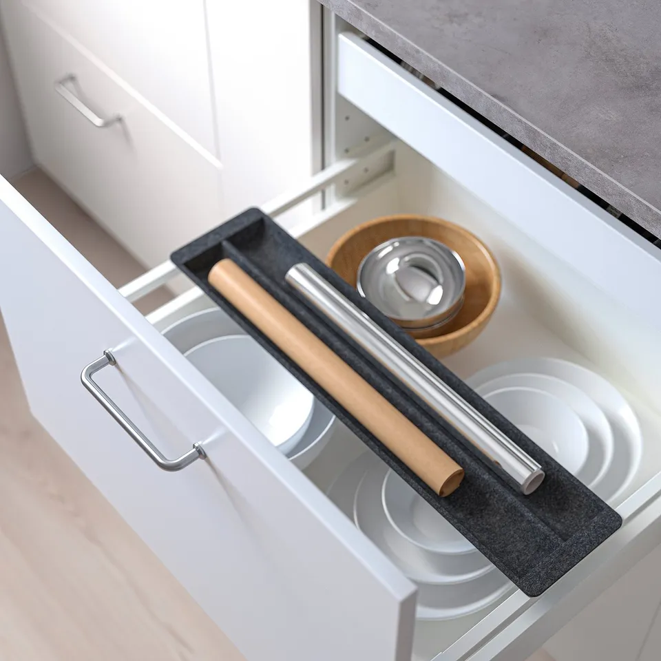 Kitchen drawer with sliding organiser holding a rolling pin and bowls, optimising space.