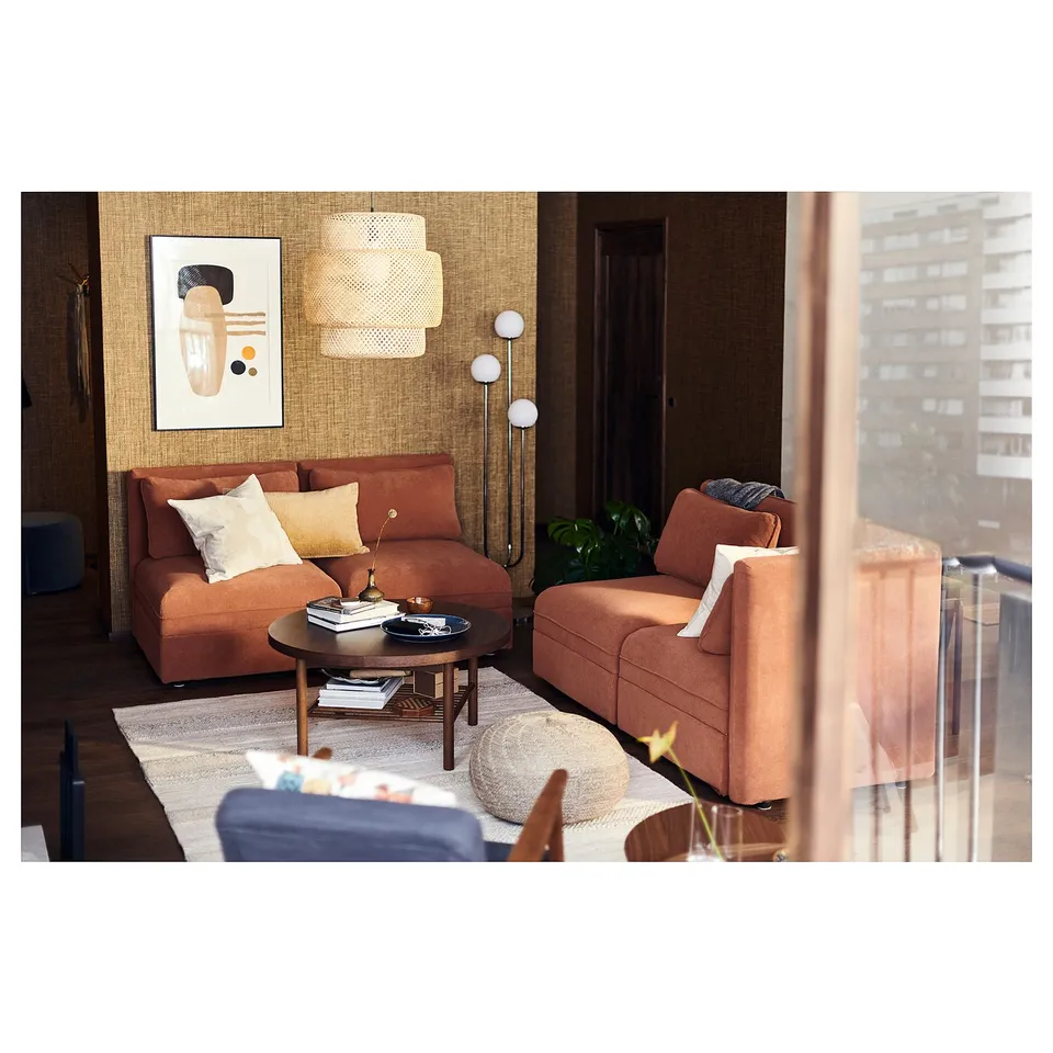 Stylish living room with brown BRÖNDEN rug, orange couches, modern hanging lamp, and abstract wall art.