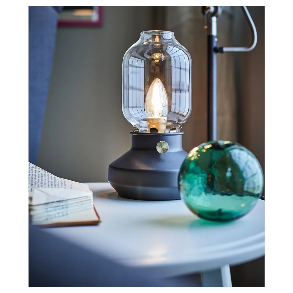 A tärnay lamp with a glass shade and black base, providing warm mood lighting.