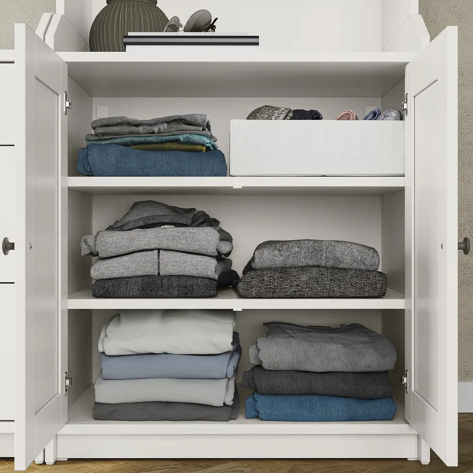White HAUGA chest with folded clothes, neatly organised in sections.