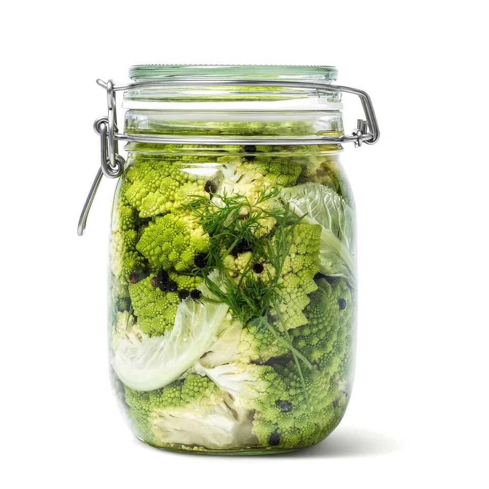 Glass jar with airtight lid, holding pickled broccoli and fennel, seals food fresh.