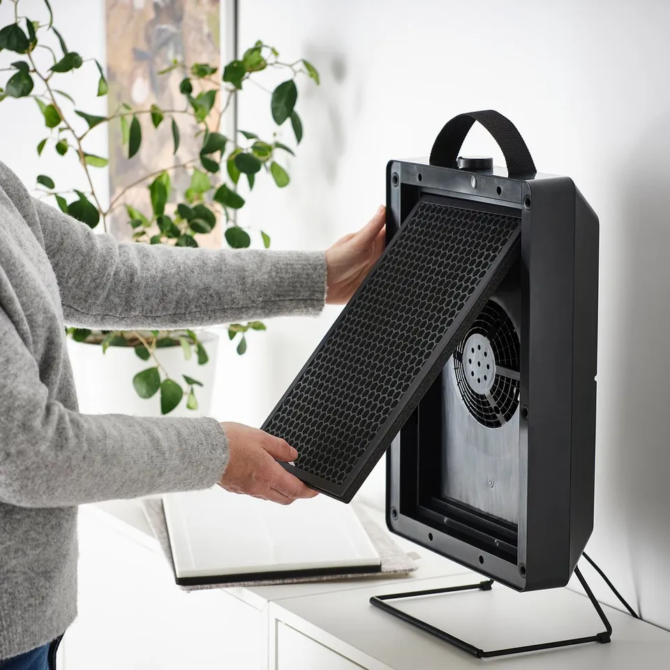 Person installing a portable air purifier with a philtre to improve indoor air quality.