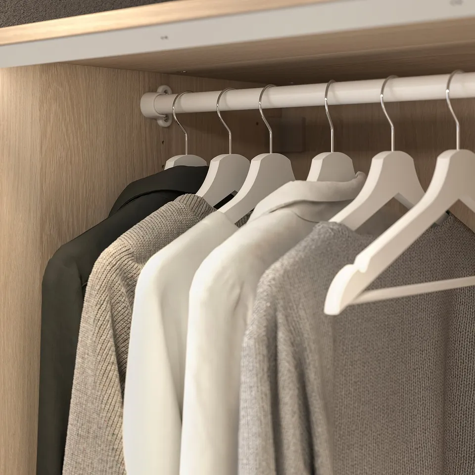 Closet with hanging rod, clothes hangers, and neatly organised clothes.