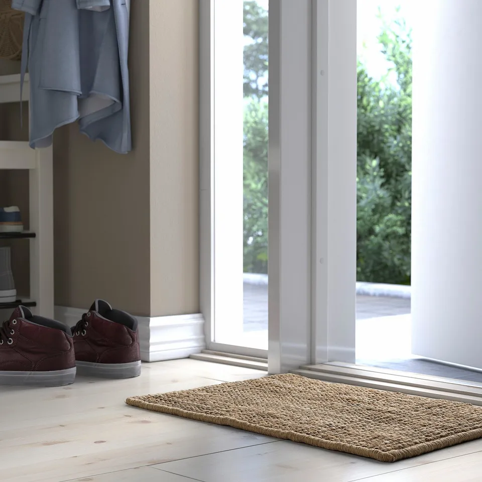 LOHALS jute mat near white doors, light brown with greenery outside.