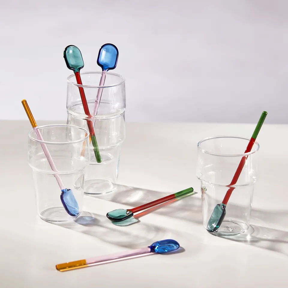 Colourful glass spoons in transparent cups, showcasing their playful design and heat-resistant functionality.