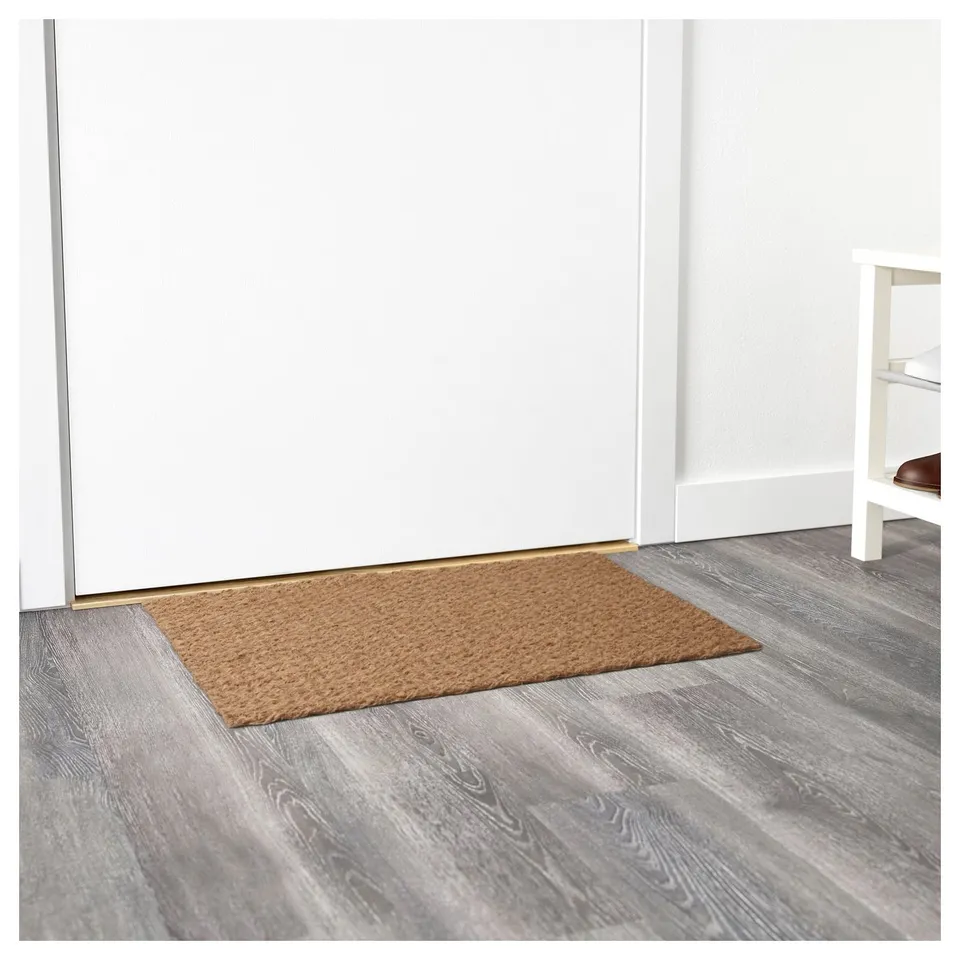 Beige coir mat at entrance, textured, sturdy backing for slip-free, clean indoors.