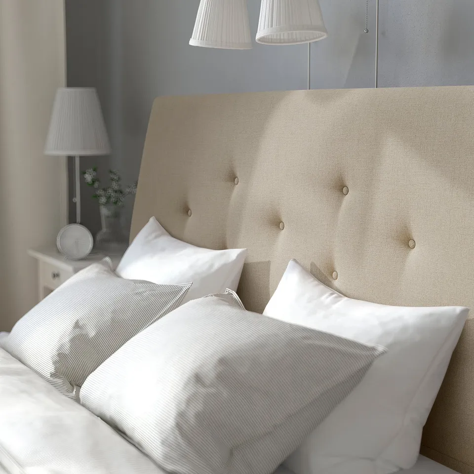 Bed with beige headboard, white pillows, lamps beside it.