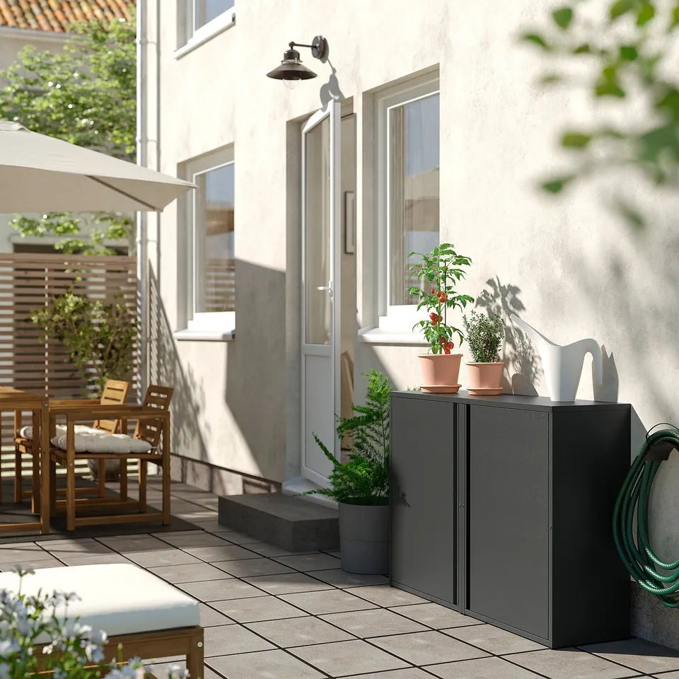 Modern outdoor space with grey SUNDSÖ cabinet, potted plants, and wooden furniture.