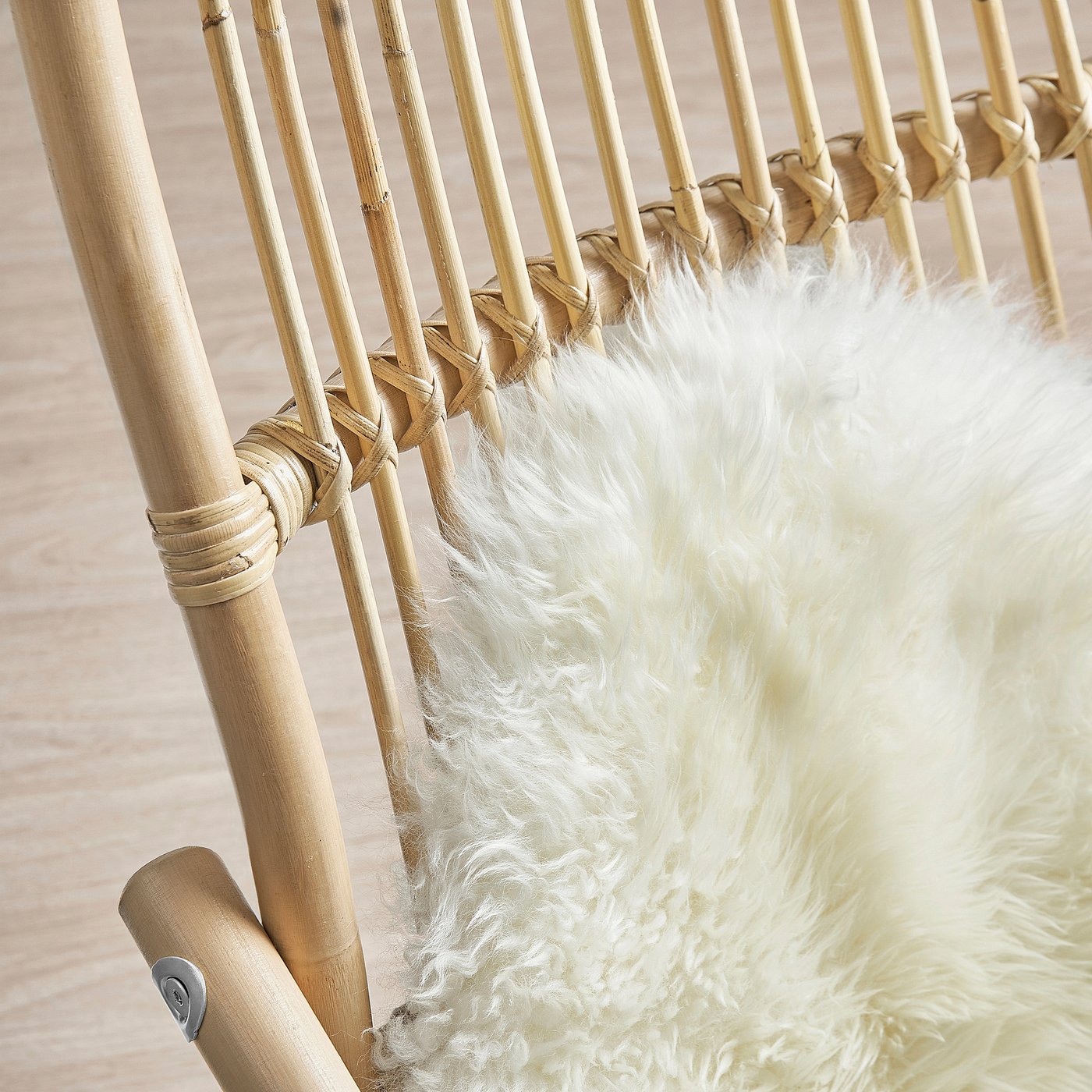 Close-up of handwoven rattan armchair with fluffy faux fur cushion.