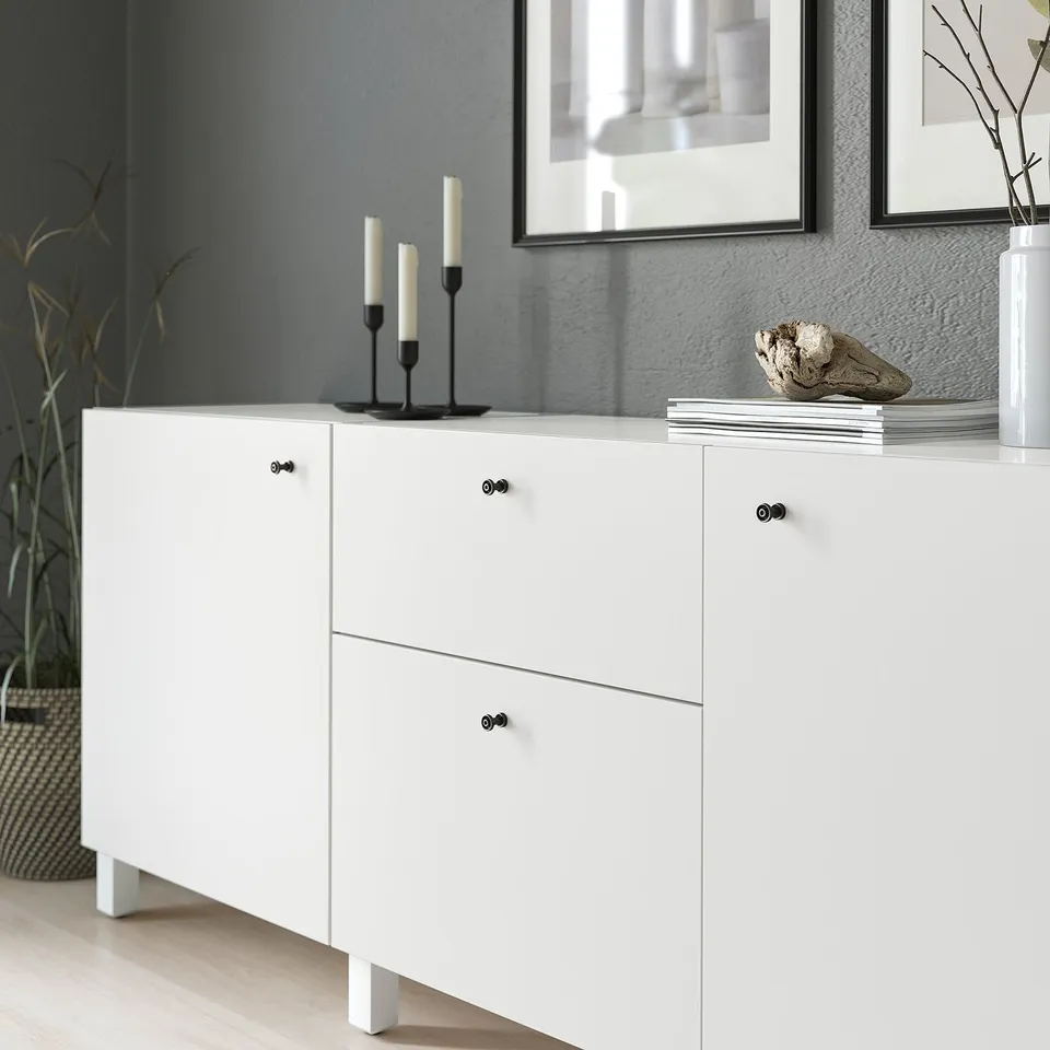 White cabinet with black knobs, displaying decor items.