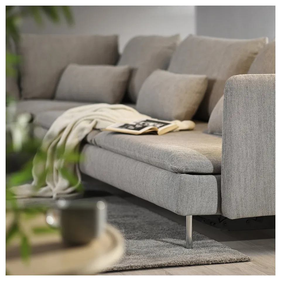Modern grey sofa bed with light wood legs, featuring multiple cushions and a cosy throw blanket. Perfect for relaxing and transforming into a bed.
