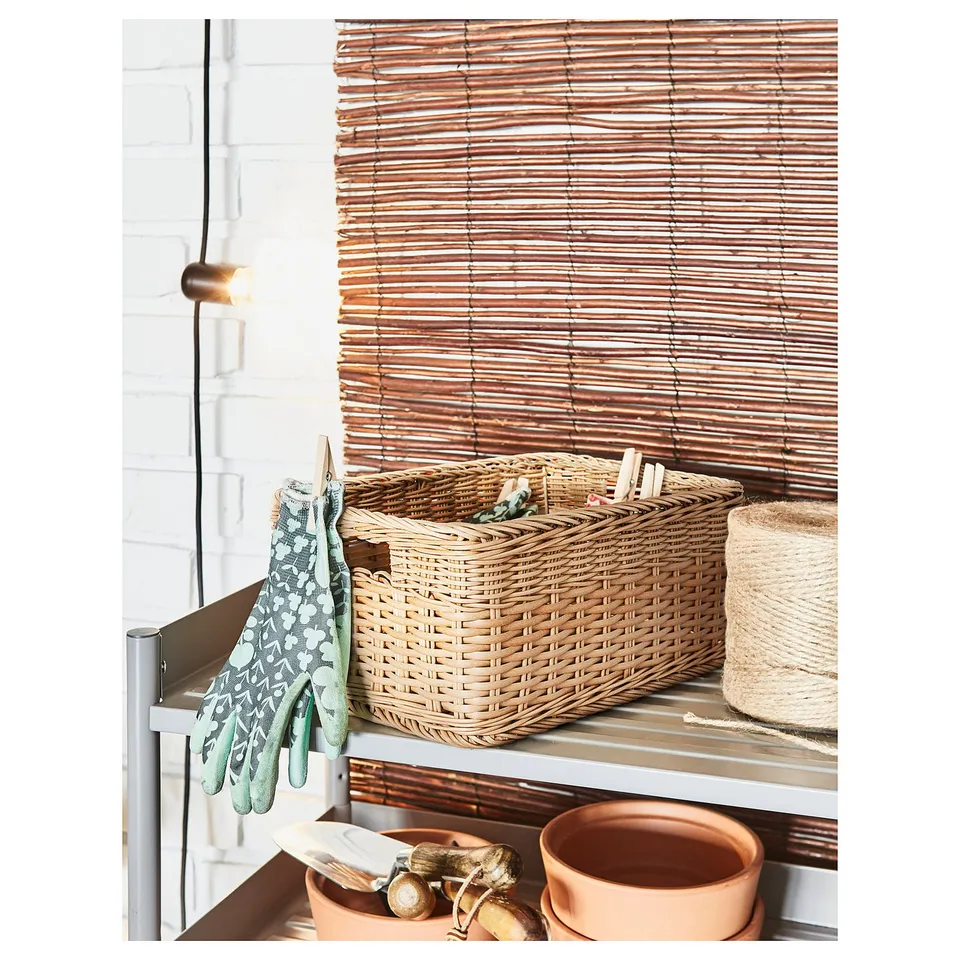 A wicker basket on a shelf with gardening tools, pots, and gloves.