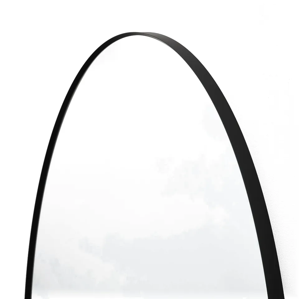 Round mirror with sleek black frame, reflecting light, mounted on wall.
